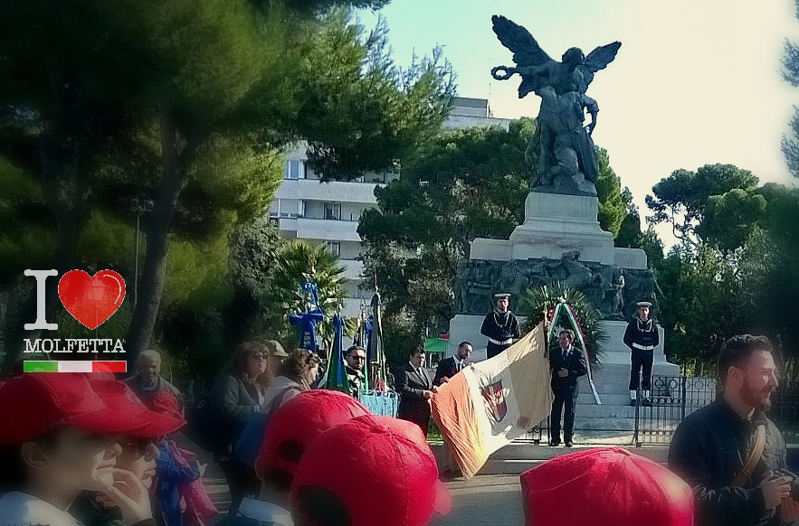 Piccoli studenti e uomini in divisa omaggiano la Bandiera